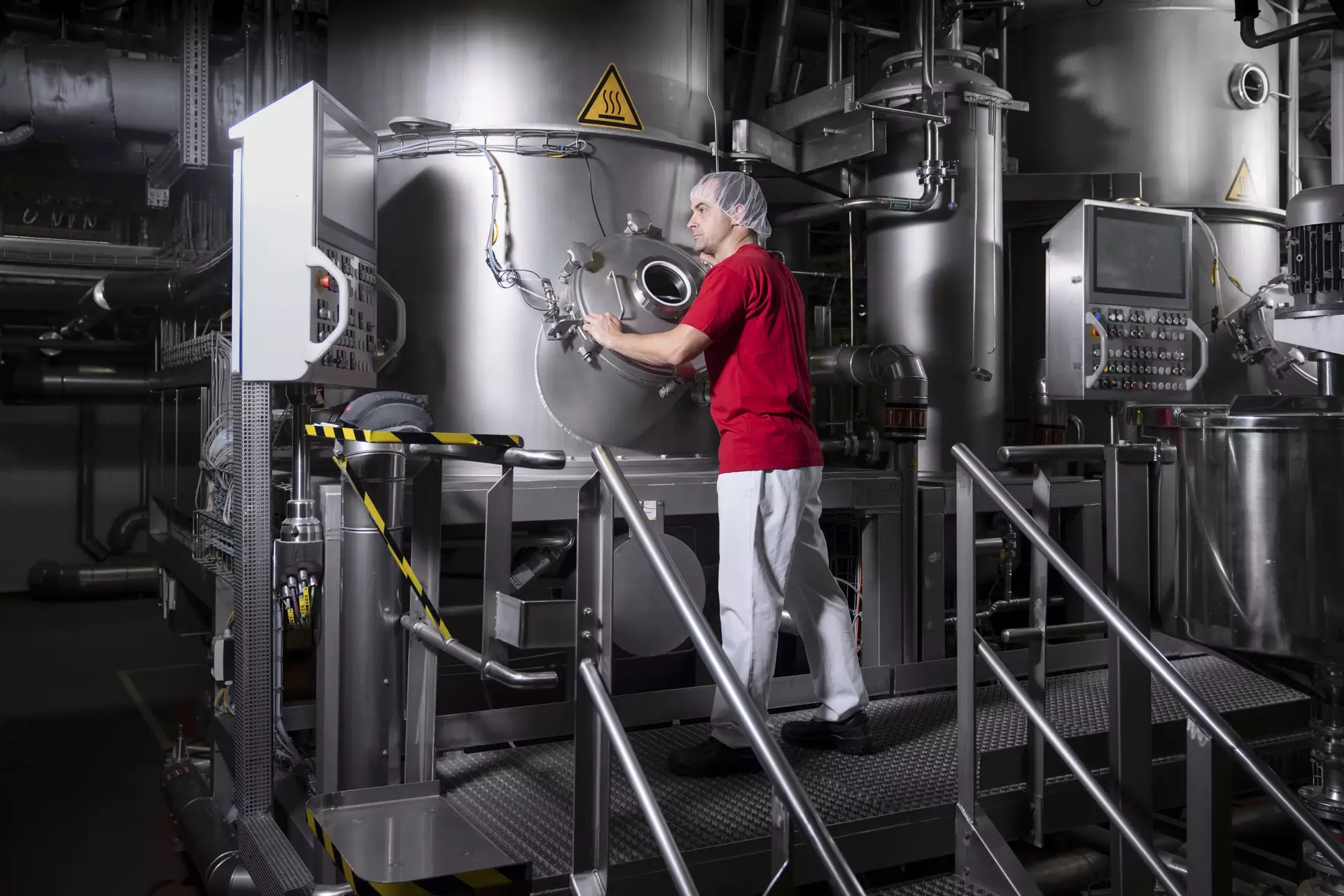 Ein Mitarbeiter in Arbeitskleidung, der einen großen Kochkessel bedient