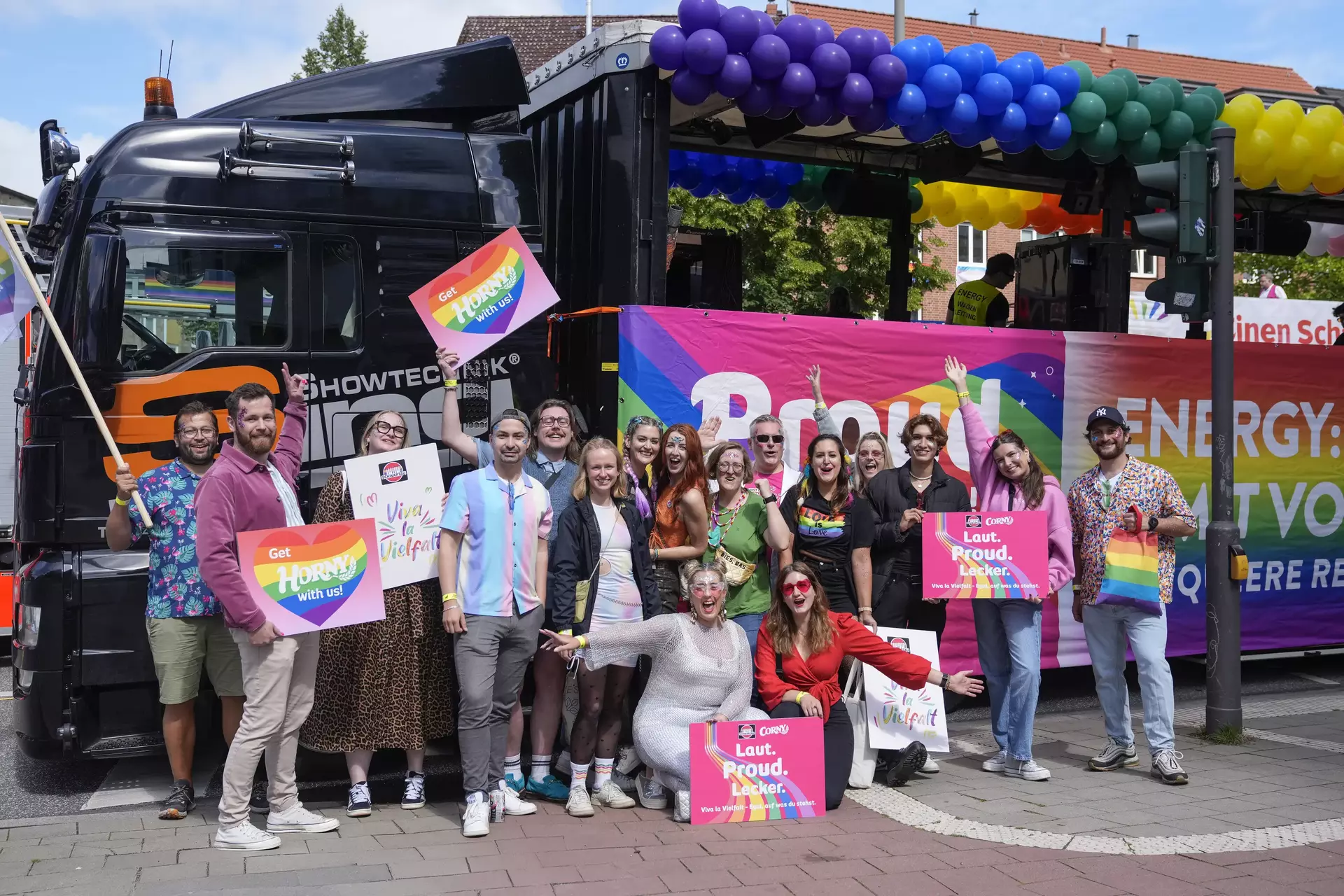 20 Personen aus Team Schwartau mit bunten Schildern vor dem CSD Truck in Hamburg