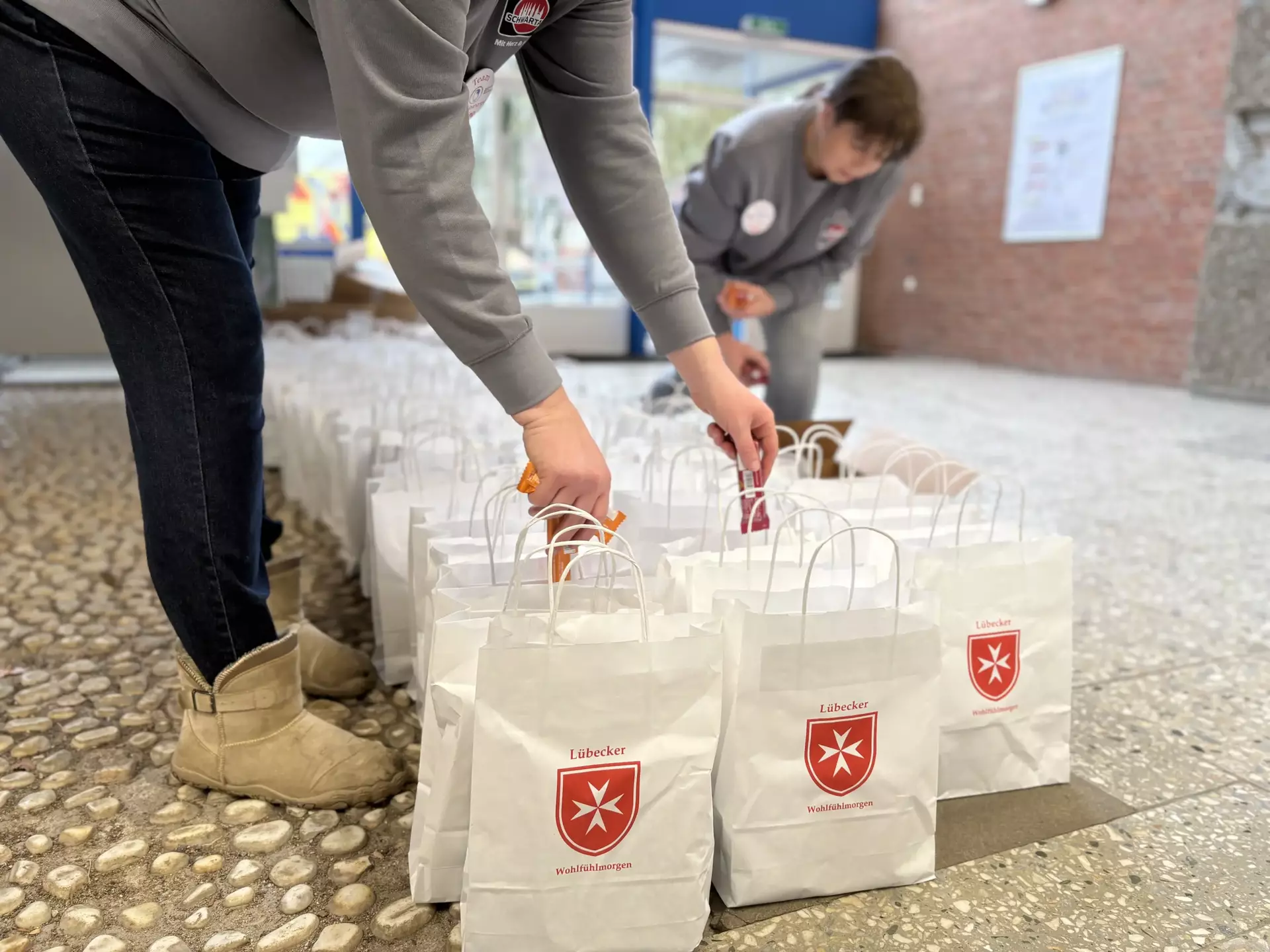 Zwei Corny Riegel werden in Goodie-Bags gesteckt, auf den Tüten steht "Lübecker Wohlfühlmorgen"
