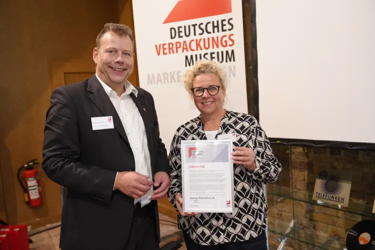 Hans-Georg Böcher, Leiter Verpackungsmuseum Heidelberg, und Bettina Gott-Schlüter, Marketingdirektorin der Schwartauer Werke mit Urkunde für den Preis "Verpackung des Jahres 2024" für Schwartau Extra
